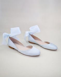 a pair of white shoes with bows on them