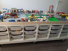 a toy train table with legos on the top and many other toys in bins