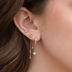 a close up of a woman's ear wearing gold and white earrings with pearls