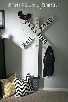 a mickey mouse sign on the side of a wall next to pillows and a coat rack