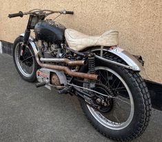 an old motorcycle parked in front of a building with dirt on the tires and seat