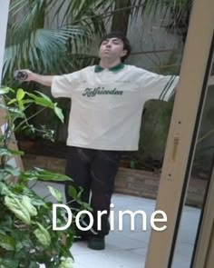 a young man standing in front of a plant