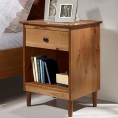 a wooden nightstand with books on it and a photo frame sitting on top of it