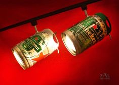 two cans of beer are hanging from the ceiling in front of a red background,