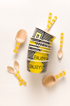 wooden spoons and cups with the word enjoy on them are scattered around each other