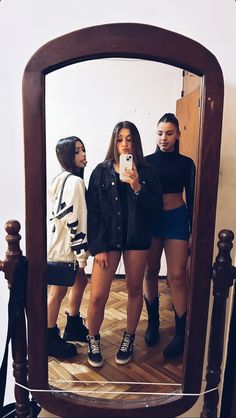 three girls are standing in front of a mirror