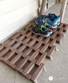 three pairs of running shoes sitting on top of a wooden slatted floor next to a door