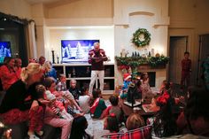 a man standing in front of a group of children sitting on couches next to a christmas tree