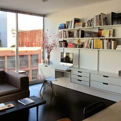 a living room filled with furniture and bookshelves next to a large glass window