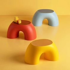 three colorful stools sitting on top of a yellow floor next to each other in front of a wall