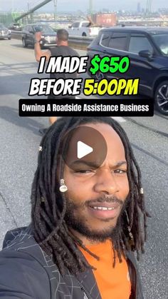 a man with dreadlocks and an orange shirt is smiling at the camera while standing in front of a black car