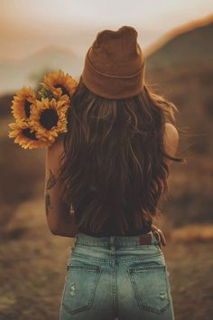 the back of a woman's head with a sunflower in her left hand