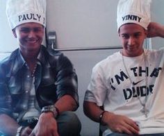 two young men sitting next to each other wearing chef's hats on their heads