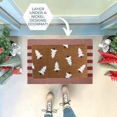 a person standing in front of a door mat with christmas trees on it and the words layer under a nickel designs doormat