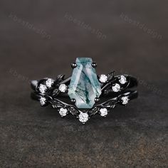 a ring with an aqua green stone surrounded by white diamonds and leaves on it, sitting on a black surface