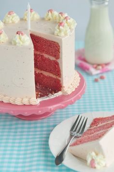 a red velvet cake with white frosting and sprinkles on a pink plate