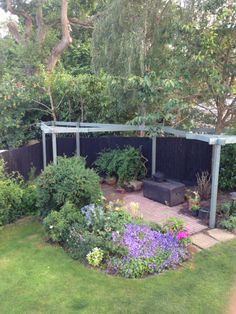 a garden with lots of flowers and plants around it in the middle of a yard