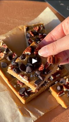 a person is picking up some kind of snack from a tray with chocolate chips and pecans