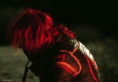 a woman with red hair is kneeling down in the dark and looking at her cell phone