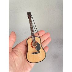 a miniature guitar is held in the palm of someone's hand with a string attached to it