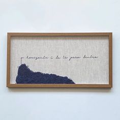 a piece of artwork hanging on the wall above a wooden frame with words written in cursive writing