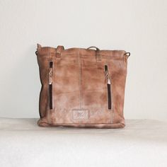 This rustic, leather travel tote is ideal for organizing your belongings on the go. Its brass brads, double exterior pocket, exterior conceal and carry pocket, interior double pocket, interior zipper pocket, and lined interior provide generous space for all your essentials. The perfect blend of functionality and style. About 11” x 14” Shipping on custom items takes 8-10 business days. Soft And Oiled Leather Travel Bags, Vintage Leather Backpack With Zipper For Everyday Use, Oiled Leather Travel Bags, Travel Bags In Soft Oiled Leather, Rugged Satchel With Leather Handles For Everyday Use, Vintage Oiled Leather Bag For Everyday Use, Rugged Leather Bag With Zipper Pocket, Rugged Brown Bag With Zipper Pocket, Rugged Leather Backpack With Leather Lining For Everyday Use