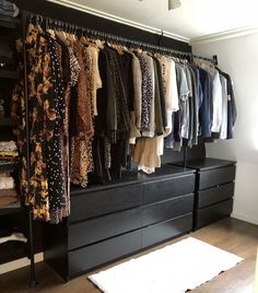 an organized closet with clothes hanging on the rail and rugs in front of it