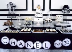 a black and white dessert table with chanel no 30 sign on the top shelf