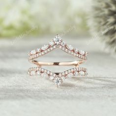 two wedding bands with diamonds on them sitting next to a pine cone shaped tree branch