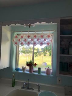 a kitchen sink under a window next to a counter top with dishes and cups on it