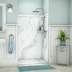 a white bathroom with blue rugs on the floor and a shower in the corner