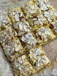 several squares of food sitting on top of a piece of paper covered in powdered sugar