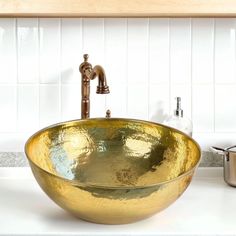 a gold bowl sink sitting on top of a white counter