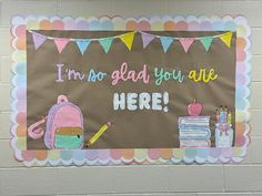 a bulletin board that says i'm so glad you are here with school supplies