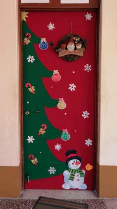 a snowman standing in front of a christmas tree on a red door with decorations