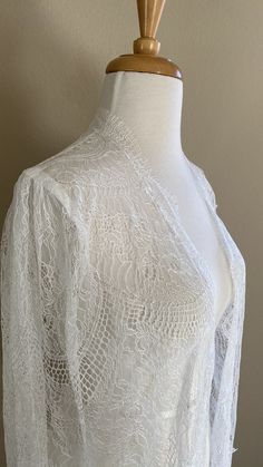 "Chantilly lace cape in off-white shade Unique fabric design with a chandelier-like motif giving an Art Deco vibe Fitted shoulders with soft gathers The cape is edged with eyelash scallop edge - very feminine Finished length is 60\" from shoulders A one-of-a-kind design💕" Lace Long Sleeve Wedding Shrug, Long Sleeve Lace Shrug For Wedding, Long Sleeve Lace Wedding Shrug, Long Sleeve Lace Cover-up With Lace Trim, White Lace Long Sleeve Cover-up, White Lace Dress For Mother Of The Bride, White Long Sleeve Lace Cover-up, Long Sleeve Lace Wedding Dress With Lace Cuffs, Elegant Scalloped Lace For Ceremonies