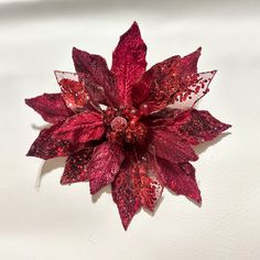 a red poinsettia on a white surface with lots of glittery flakes