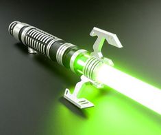 a green light saber is on top of a black surface with a metal object attached to it