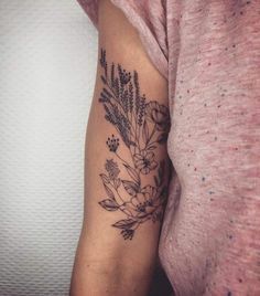 a woman's arm with flowers and leaves tattooed on the left side of her arm