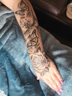 a woman's arm with butterflies and roses tattoo on her left arm, which is black and grey