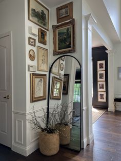 a large mirror sitting on top of a wooden floor next to a wall filled with pictures