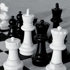 black and white chess pieces sitting on top of a checkered floor