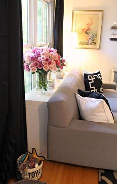 a living room filled with furniture and flowers on top of a table in front of a window