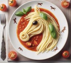 a white plate topped with spaghetti and a horse head made out of tomato slices on top of it