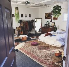 an open door leading to a bedroom with lots of clothes on the floor and rug