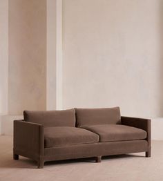 a brown couch sitting on top of a hard wood floor next to a white wall