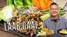 a man holding a plate full of food with the words laab gaai in front of him