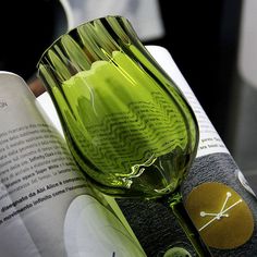 a green glass sitting on top of an open book