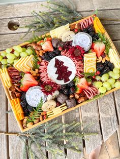 a platter with fruit, cheese and meats in it on a wooden table