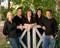 a group of people standing next to each other near a wooden fence in the woods